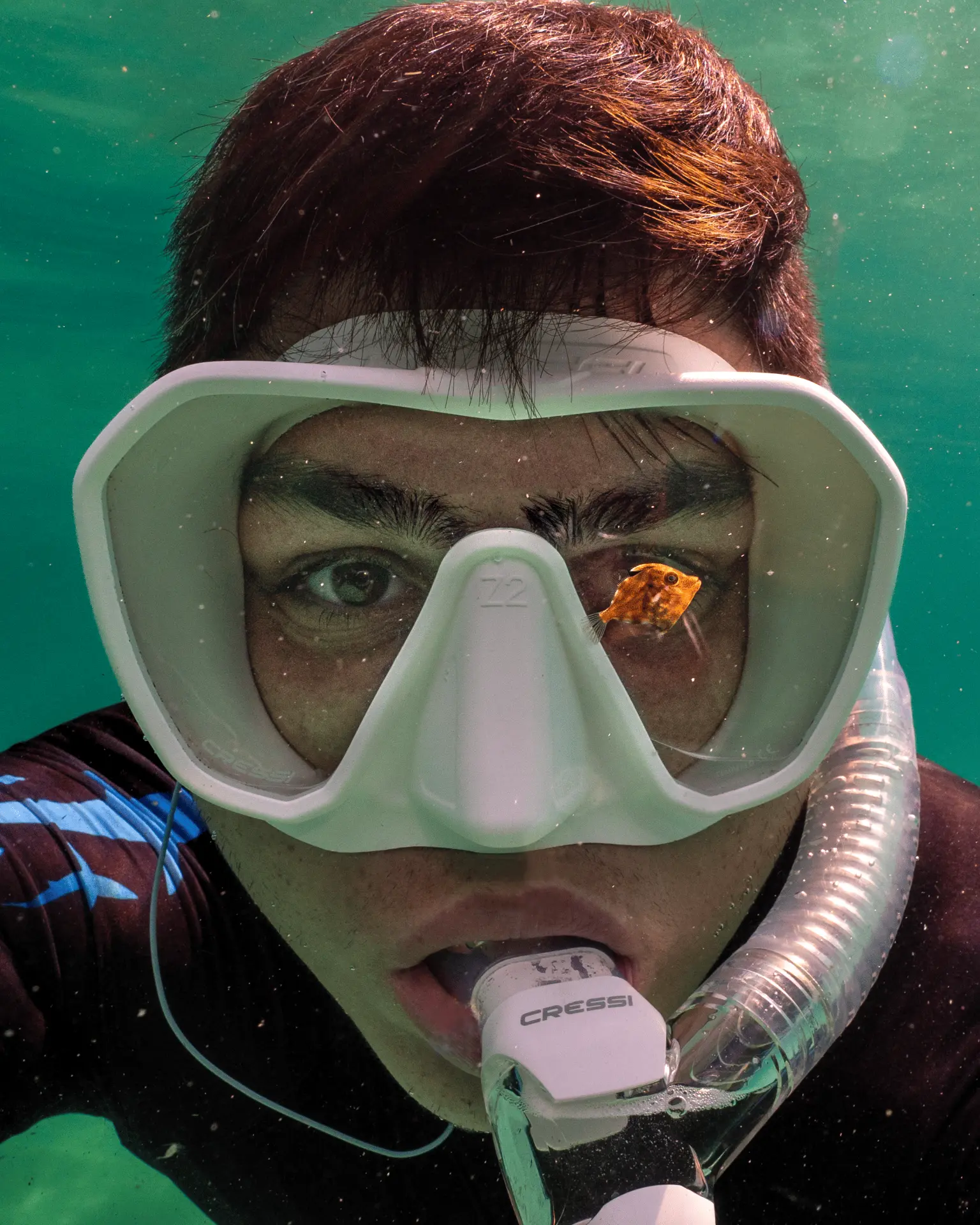 Victor Bezerra underwater wearing a diving mask beside a small fish